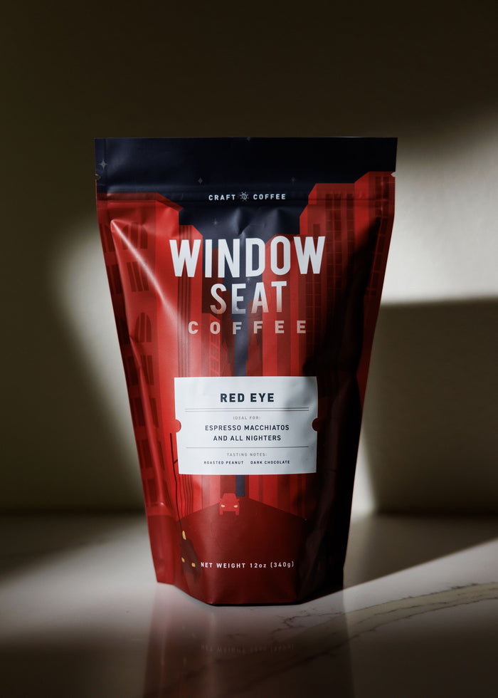 Red and black coffee bag labeled 'Window Seat Coffee' on a dark background